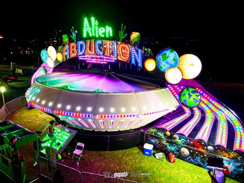 Neon-lit spinning ride glowing at night at Pied Piper's Haunted Carnival 2023
